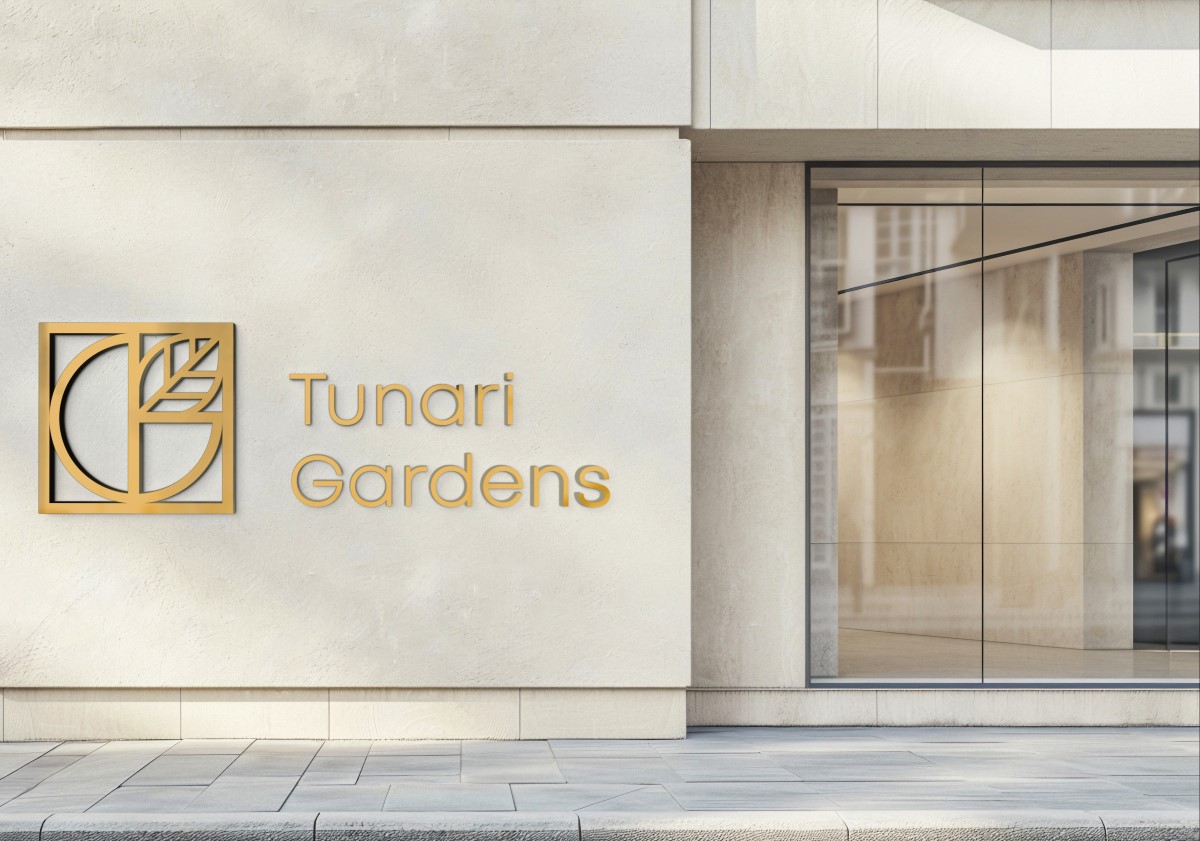 Tunari Gardens logo in gold on the exterior wall of a modern building entrance