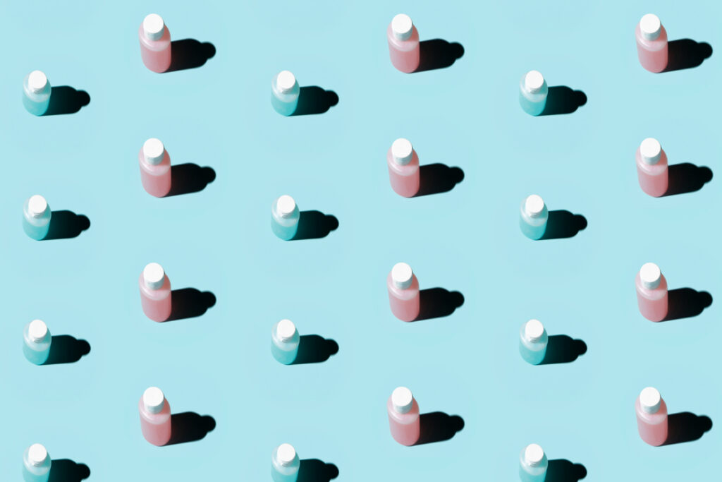 Repeating pattern of identical push pins on a pale blue background