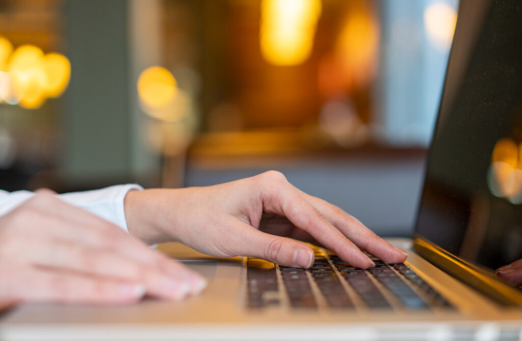 Close-up of hands typing on a laptop keyboard in a warmly lit room