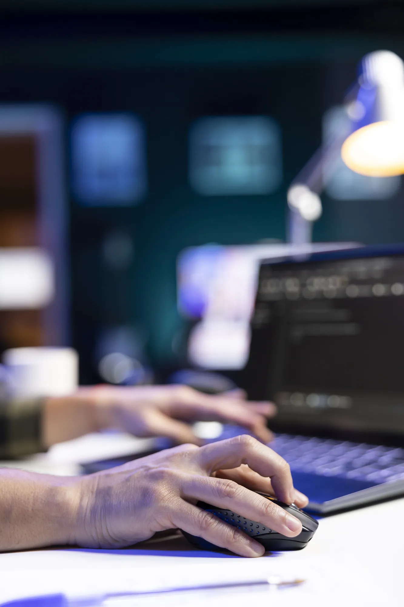 Close-up of hands typing at a laptop keyboard in a dimly lit office